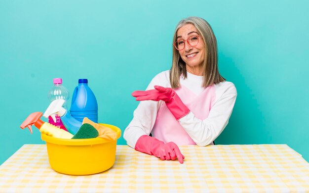 Femme senior aux cheveux gris souriant joyeusement se sentant heureuse et montrant un concept de concept de femme de ménage