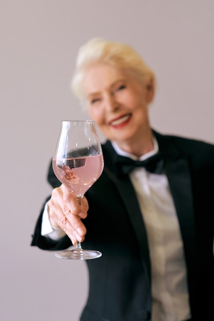 Femme senior élégante sommelier mature en smoking avec verre de vin