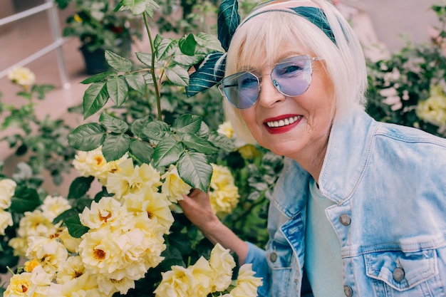 Femme Senior élégante En Veste En Jean Faisant Du Selfie Avec Des Fleurs Jardinage Voyageant Ambiance Positive