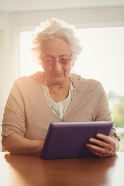 Femme senior focalisée avec tablette à la maison
