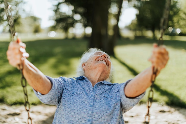 Femme senior joyeuse sur une balançoire sur un terrain de jeu