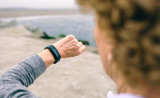 Femme senior méconnaissable regardant sa montre intelligente