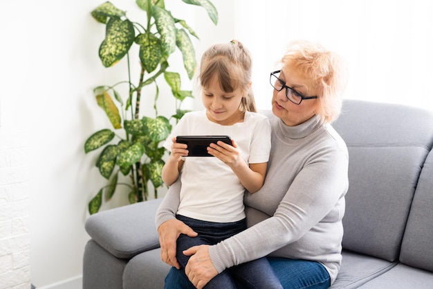 Femme senior avec petit-enfant jouant au jeu sur smartphone.