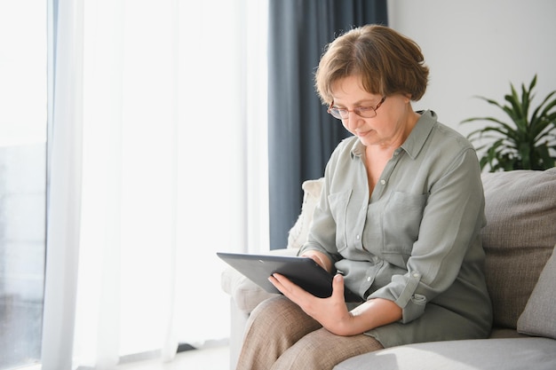 Femme senior souriante à la maison connectée sur internet