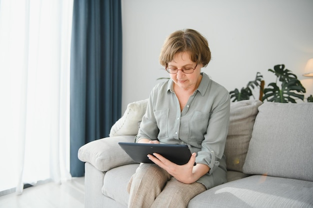 Femme senior souriante à la maison connectée sur internet