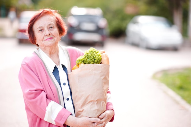 Femme senior souriante tenant un sac à provisions avec de la nourriture