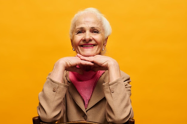 Femme senior souriante en tenue décontractée intelligente assise devant la caméra