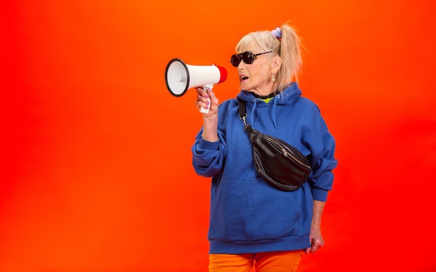 Femme senior en tenue ultra tendance isolée sur un mur orange vif