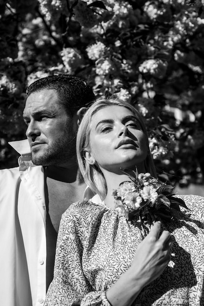 Femme sensuelle et homme en fleurs roses dans le parc de fleurs d'été