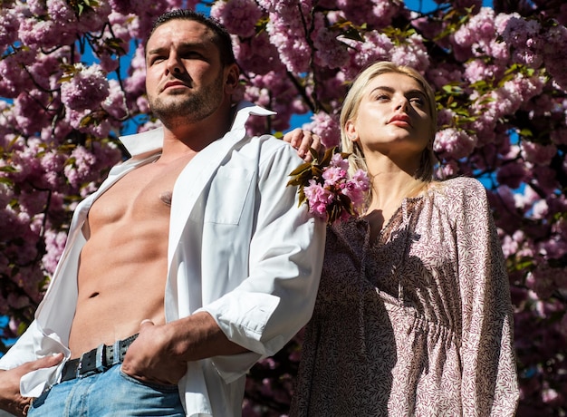 Femme sensuelle et homme en fleurs roses dans le parc de fleurs d'été