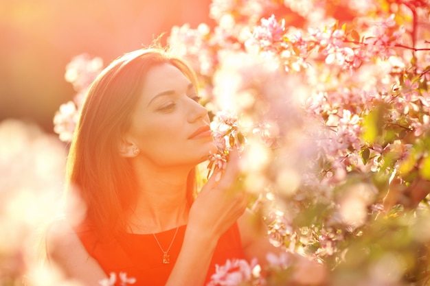 femme sent les fleurs dans le jardin de printemps