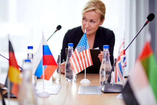 Femme sérieuse concentrée en costume à la conférence, écoutant les discussions des partenaires, lors d'une réunion multiethnique sans liens. entreprise, concept de sommet