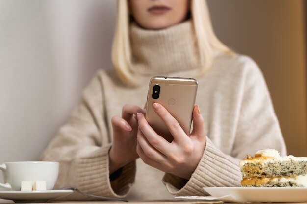 Femme sérieuse regardant téléphone intelligent vérifiant les nouvelles sur un café.