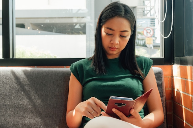 Une femme sérieuse utilise son smartphone sur le canapé dans un coin du café.