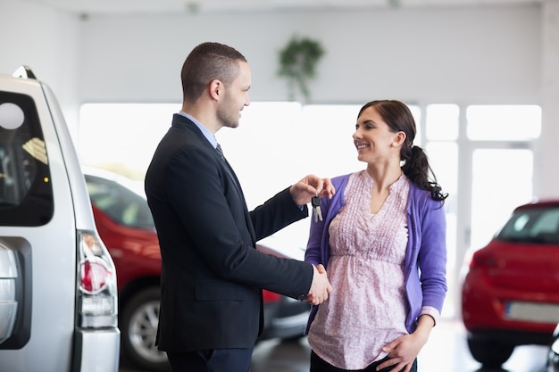 Femme serrant la main d&#39;un vendeur tout en recevant des clés de voiture