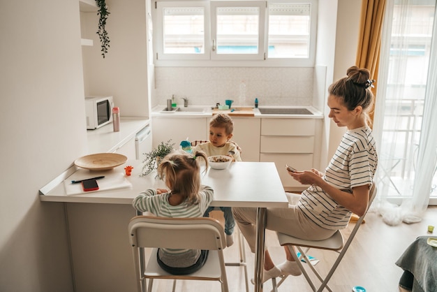 Femme et ses enfants assis dans la cuisine