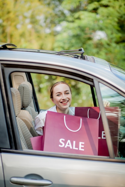 Femme Avec Ses Sacs à Provisions Dans La Voiture - Concept De Shopping.