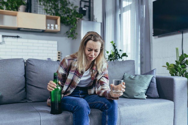 Femme seule à la maison chagrin et dépression buvant de l'alcool fort alcoolique assis à la maison sur le canapé