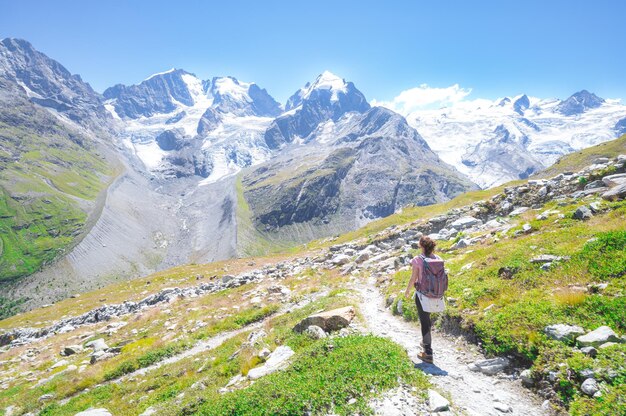 Une femme seule marche sur un sentier de haute montagne