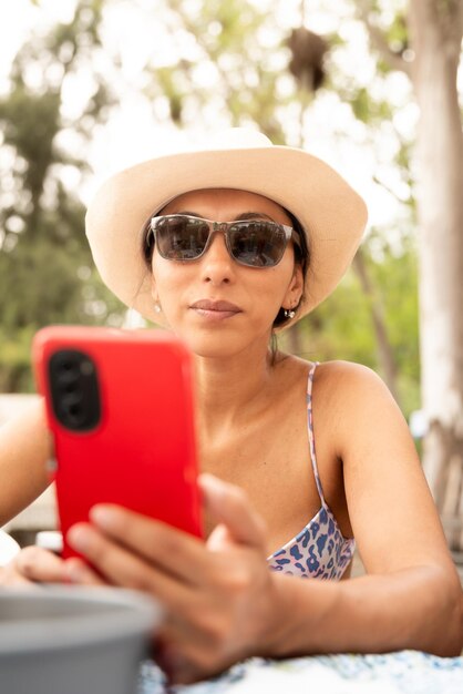 Une femme seule profitant d'un pique-nique l'après-midi en vérifiant son smartphone.