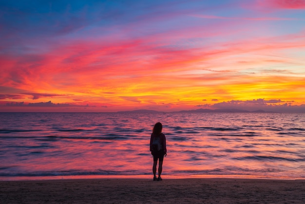 Femme seule se détendre sur le ciel romantique de la plage de sable au coucher du soleil. De vraies personnes s'éloignent de tout. Nuages spectaculaires au-dessus de la mer ondulante en hiver.