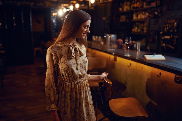 Femme seule avec un verre de vin assis au bar