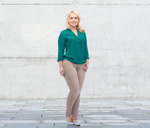 femme, sexe, portrait, taille plus et concept de personnes - jeune femme souriante en chemise et pantalon sur fond de béton urbain