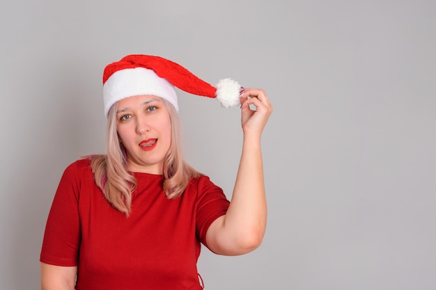 Femme sexy adulte dans un bonnet de Noel avec des lèvres rouges et une langue séduisante sur fond gris, copyspace