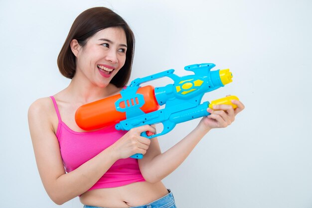 Femme sexy asiatique avec de l'eau de pistolet à la main sur fond blancFestival songkran day en thaïlandeLe meilleur du festival de la thaïlande du sourire