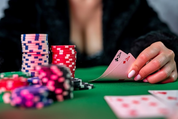 Femme sexy avec des cartes de poker et des jetons dans les mains jouant au poker à la table