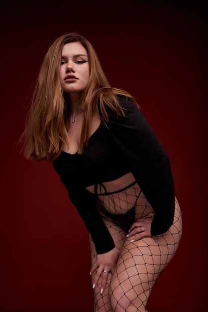 femme sexy en collants résille noirs en studio sur fond rouge