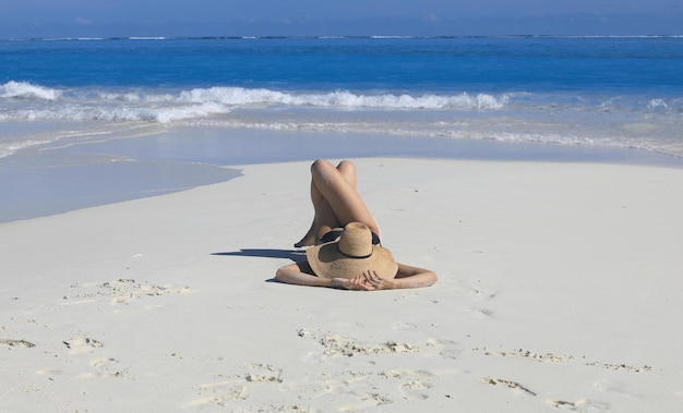 femme sexy dans un chapeau de paille se trouve sur le sable de la mer