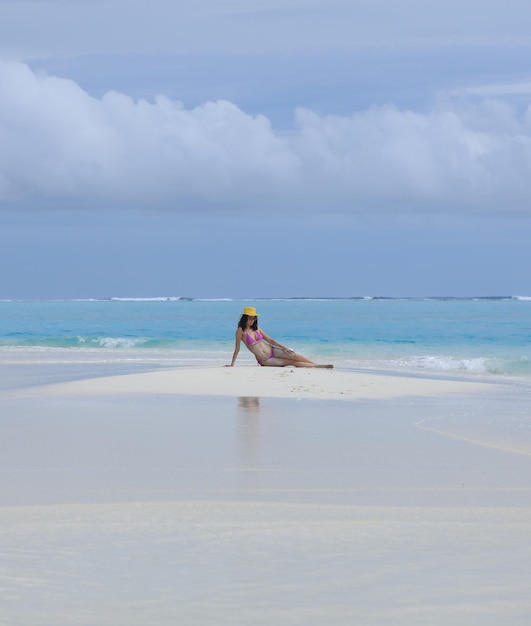 femme sexy dans un chapeau de paille se trouve sur le sable de la mer