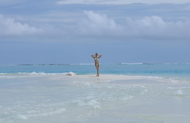 femme sexy dans un chapeau de paille se trouve sur le sable de la mer