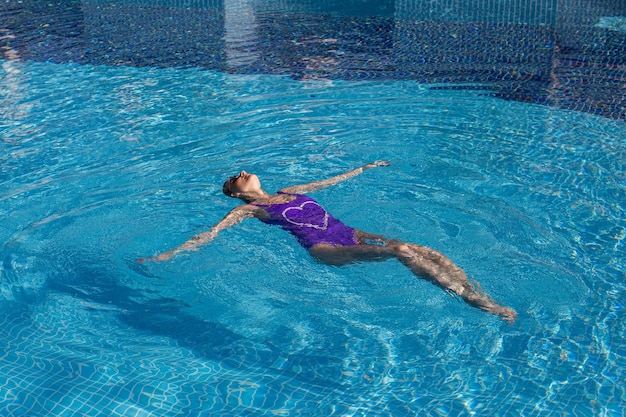 Femme sexy élégante en bikini blanc sur le corps mince et galbé bronzé pose près de la piscine