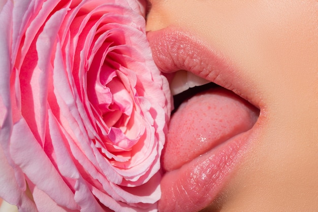 Femme sexy embrassant les lèvres d'une fleur rose rouge avec du rouge à lèvres gros plan Lèvres de belle femme avec une fille rose bl...