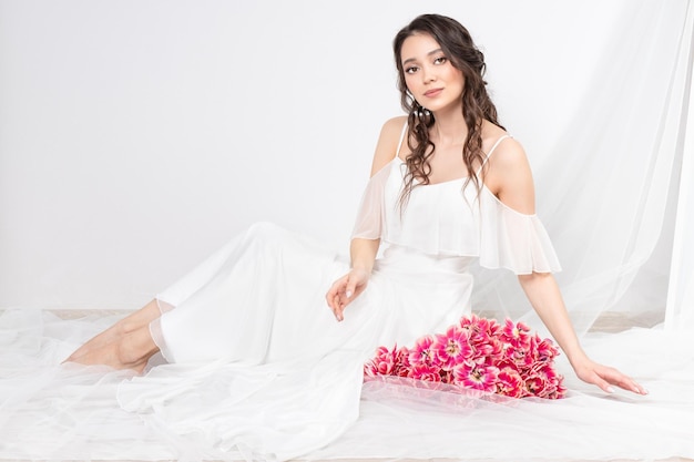 Femme sexy avec des fleurs tulipes roses dans les mains sur un fond clair