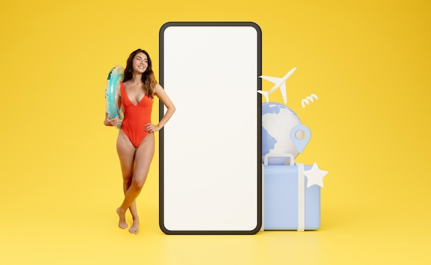 Femme sexy en maillot de bain debout devant un énorme collage de maquette de téléphone