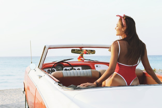 Femme sexy en maillot de bain rouge et voiture cabriolet rétro