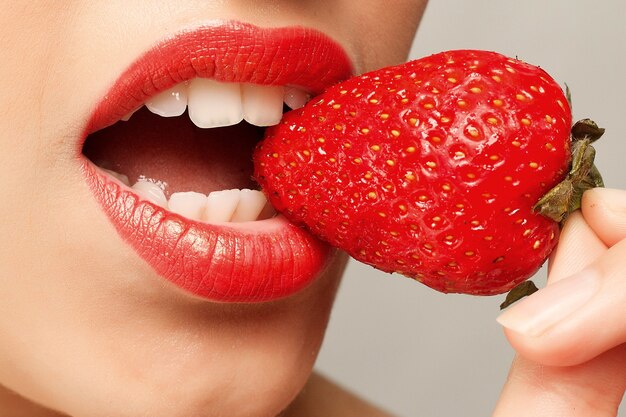 Femme sexy mangeant des fraises. Lèvres sensuelles.