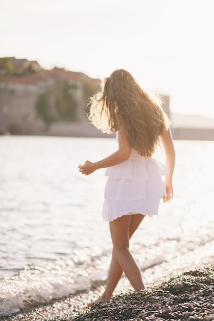 Femme sexy marche sur la plage au coucher du soleil