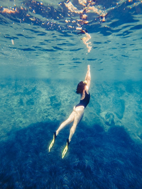 Femme sexy nageant sous l'eau dans un masque de plongée avec palmes vacances d'été