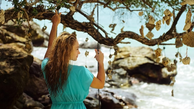 Femme sexy passe ses vacances au bord de la mer La fille se balance sur une balançoire Concept joyeuses fêtes joie légèreté air frais propreté et santé