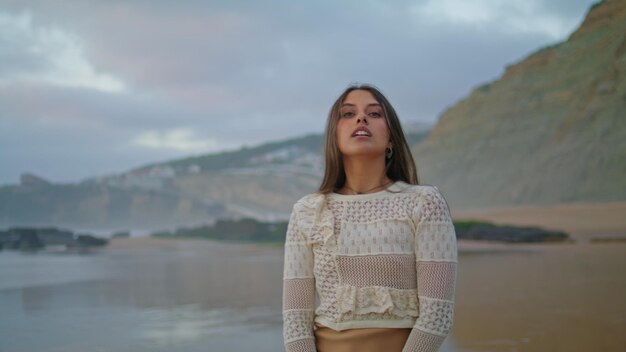 Une femme sexy se déplaçant sensuellement sur le rivage en gros plan, un modèle riant posant le soir.