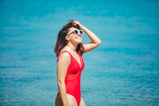 Femme sexy souriante en maillot de bain rouge dans l'eau de mer