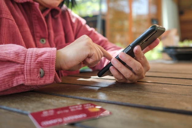 Femme shopping en ligne avec carte de crédit au café en plein air. gros plan main tenant le smartphone
