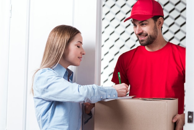 Photo femme signe la livraison avec messagerie garçon en uniforme rouge