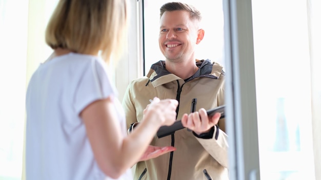 Femme signe sur une tablette pour le colis du courrier à la maison