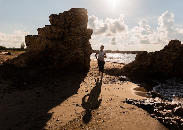 Femme silhouette courir et faire de l'exercice sur le coucher de soleil sur la plage. Sport et mode de vie sain. Nouveau départ de journée et loisirs.