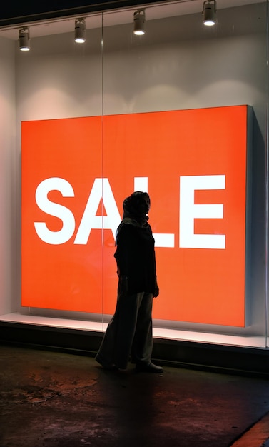 Photo une femme en silhouette debout devant un panneau de vente dans un magasin